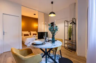 a living room with a table and chairs and a bed at Le Boréal - Studio Confort Lit Queen Size in Mazamet