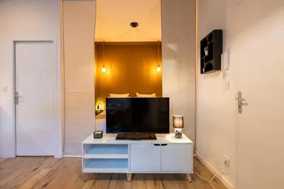 a living room with a tv on a white cabinet at Le Boréal - Studio Confort Lit Queen Size in Mazamet