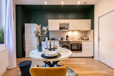 a kitchen with a table and chairs in a room at Le Boréal - Studio Confort Lit Queen Size in Mazamet
