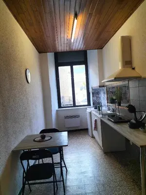 a kitchen with a table and two chairs and a sink at Le petit paradis in Saint-Pons-de-Thomières