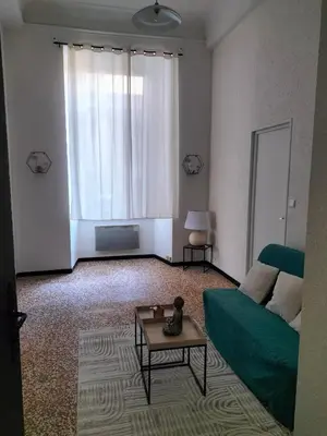 a living room with a green couch and a table at Le petit paradis in Saint-Pons-de-Thomières