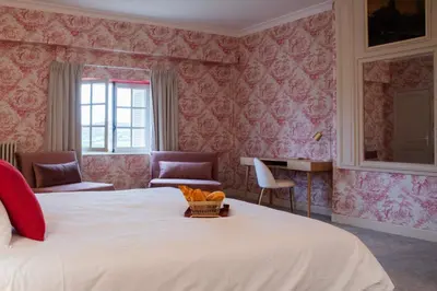 a bedroom with a large bed with pink wallpaper at Château de Roques in Teilhet