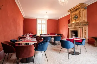 a dining room with tables and chairs and a fireplace at Château de Roques in Teilhet