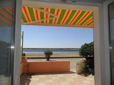 an open door to a patio with a view of the beach at Front de plage du Grazel - Piscine et parking GN500-014 in Gruissan
