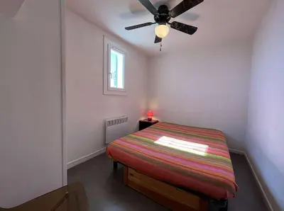 a bedroom with a bed and a ceiling fan at Front de plage du Grazel - Piscine et parking GN500-014 in Gruissan