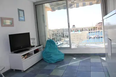 a living room with a tv and a large window at Appartement avec terrasse et jolie vue sur port GN580-033 in Gruissan