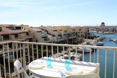 a balcony with a table and chairs and a marina at Appartement avec terrasse et jolie vue sur port GN580-033 in Gruissan