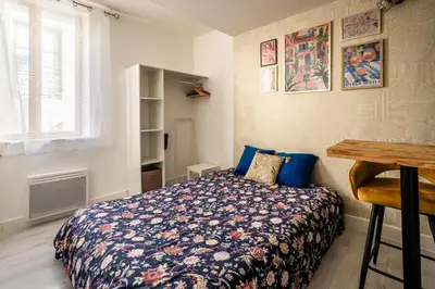 a bedroom with a bed and a table and a window at Studio Soleil d'Azur in Narbonne