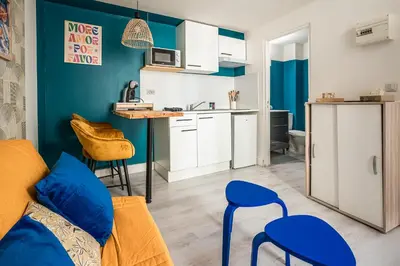 a living room with a couch and a kitchen at Studio Soleil d'Azur in Narbonne