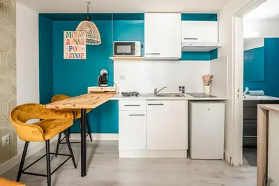 a kitchen with blue walls and a wooden table and chairs at Studio Soleil d'Azur in Narbonne