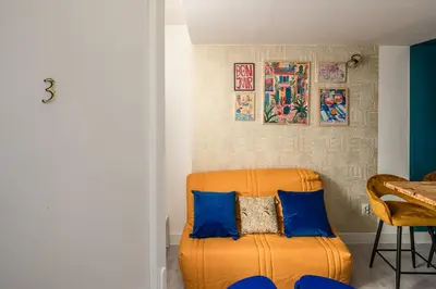 a room with a orange chair with blue pillows at Studio Soleil d'Azur in Narbonne