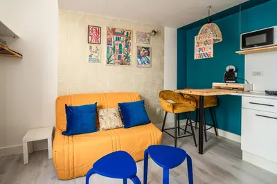 a living room with a orange couch and blue chairs at Studio Soleil d'Azur in Narbonne