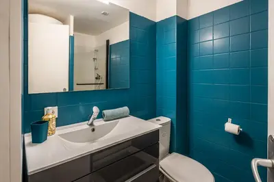 a bathroom with blue tiles and a sink and a toilet at Studio Soleil d'Azur in Narbonne