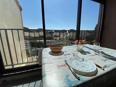a table with a plate and fork and knife on a balcony at Appartement dernier étage à 300 m de la plage GN020-238 in Gruissan