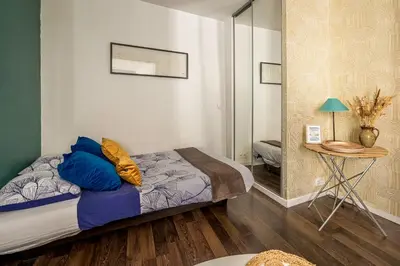 a bedroom with a bed and a table and a mirror at Joli studio Narbonne in Narbonne
