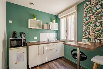 a small kitchen with green walls and white cabinets at Joli studio Narbonne in Narbonne