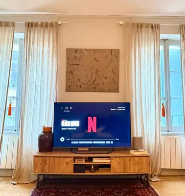 a television on a wooden table in a living room at Casa amore, cœur de ville in Carcassonne