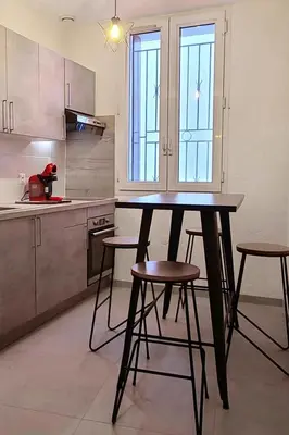 a kitchen with a table and some stools in it at Le Marceau Cour Extérieure in Narbonne