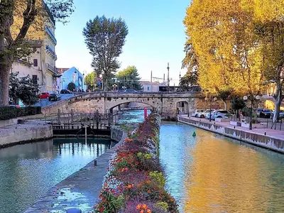 a river in a city with a bridge at Le Marceau Cour Extérieure in Narbonne