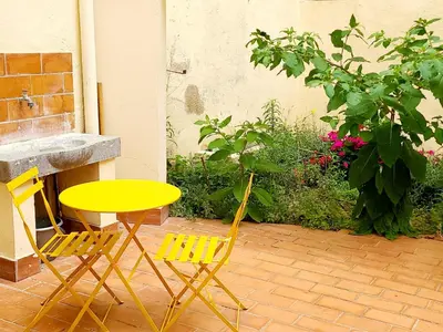 a yellow table and two chairs on a patio at Le Marceau Cour Extérieure in Narbonne