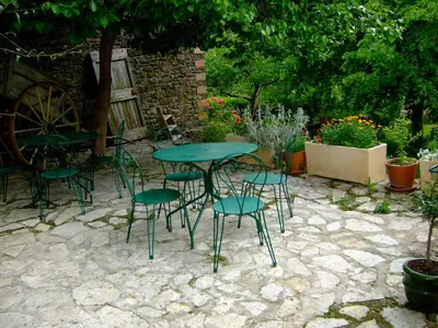 a green table and chairs on a stone patio at La Maison des Couleurs in Saint-Jean-de-Paracol