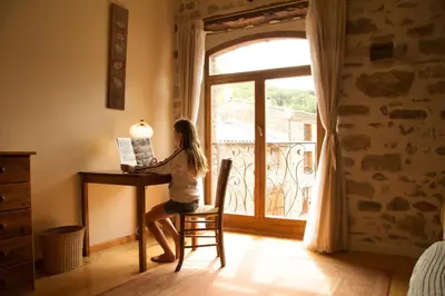 a woman sitting at a desk in front of a window at La Maison des Couleurs in Saint-Jean-de-Paracol