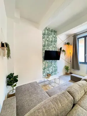 a living room with a couch and a tv on a wall at Narbonne centre Dame Nature in Narbonne