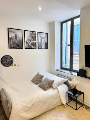 a white bedroom with a bed and some windows at Narbonne centre New york in Narbonne