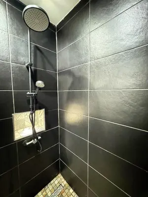 a black tiled bathroom with a shower at Narbonne centre New york in Narbonne