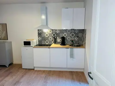 a kitchen with white cabinets and a wooden floor at Henri ll l Terrasse l Proche gare & Centre ville in Castres