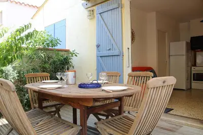 a wooden table with chairs and a tableasteryasteryasteryasteryasteryasteryasteryastery at Maison 2 pièces 4 couchages PORT LA NOUVELLE PN000-042 in Port-la-Nouvelle