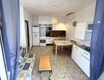 a small kitchen with a table and a dining room at Maison 2 pièces 4 couchages PORT LA NOUVELLE PN000-042 in Port-la-Nouvelle