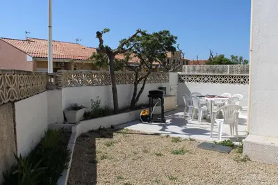 a patio with a table and chairs and a fence at Maison 6 couchages - PORT LA NOUVELLE PN000-053 in Port-la-Nouvelle