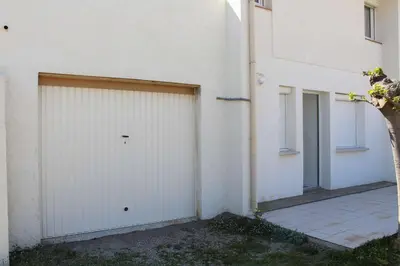 a white building with a garage door and a tree at Maison 6 couchages - PORT LA NOUVELLE PN000-053 in Port-la-Nouvelle
