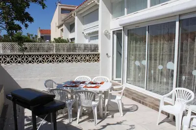 a patio with white chairs and a table and a table and chairsktop at Maison 6 couchages - PORT LA NOUVELLE PN000-053 in Port-la-Nouvelle