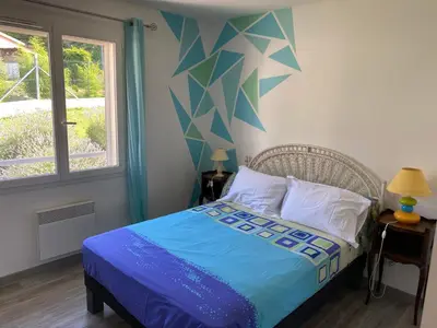 a bedroom with a bed with a blue comforter and a window at MAISON 119m2 in Revel