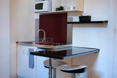 a kitchen with a sink and a counter with stools at Les 5 Lys in Carcassonne