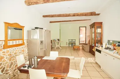 a kitchen and living room with a wooden table and chairs at Maison village T5 in Fitou