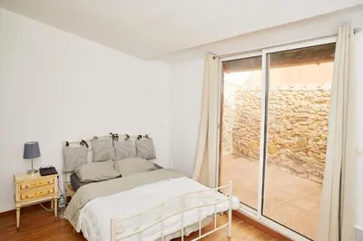 a white bedroom with a bed and a window at Maison village T5 in Fitou