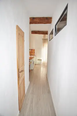 an empty hallway with a door and a kitchen at Maison village T5 in Fitou