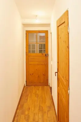 an empty hallway with a wooden door and wooden floors at Maison village T5 in Fitou