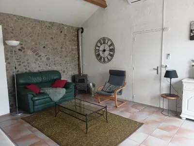a living room with a green couch and a clock on the wall at Villa L'Oustalet in Douzens