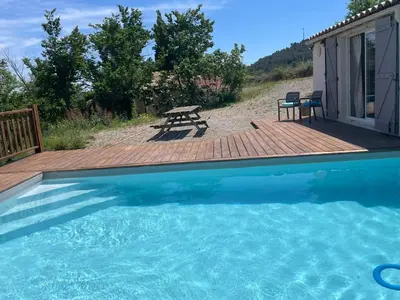 a swimming pool with a deck and a picnic table at Villa L'Oustalet in Douzens