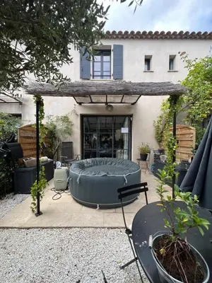 an outdoor patio with a large round bed in front of a house at Maison T3 avec spa in Saint-Laurent-de-la-Cabrerisse
