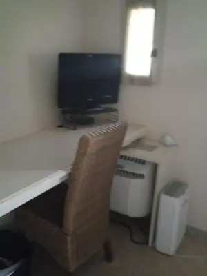 a computer desk with a monitor and a chair at Maison T3 avec spa in Saint-Laurent-de-la-Cabrerisse