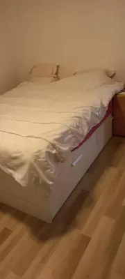 an unmade bed in a bedroom with a wooden floor at Maison calme in Payrin-Augmontel