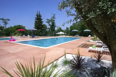 a large swimming pool with chairs and umbrellas at La Bastide in Mazères