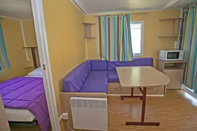 a small room with a purple couch and a bed at La Bastide in Mazères