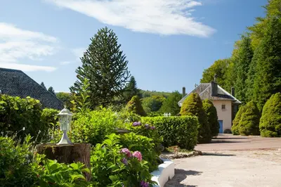 a garden with flowers and a house in the background at L'ECRIN DU LAC - Ô Cèpes in Mazamet