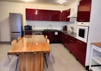 a kitchen with red cabinets and a wooden table at L'Atelier Cosy in Lézignan-Corbières